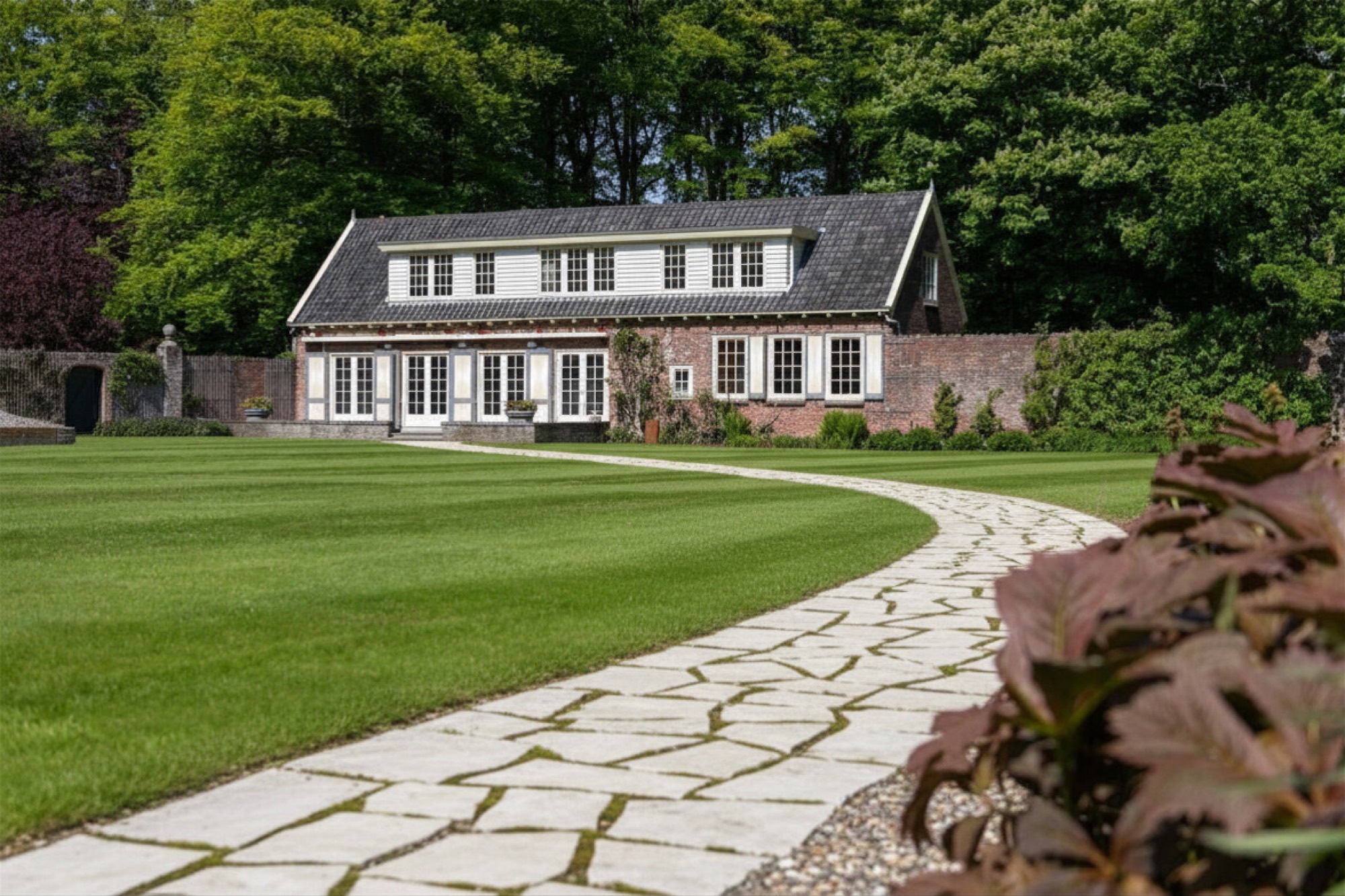Wit tuinhuis met gazon en natuurstenen pad